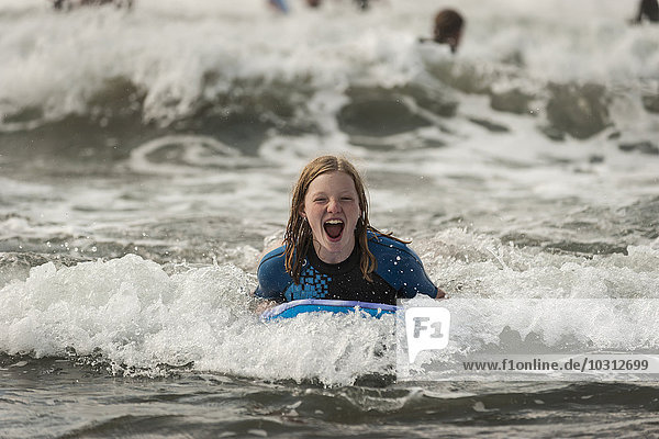 Portrait of screaming teenage girl with surfboard