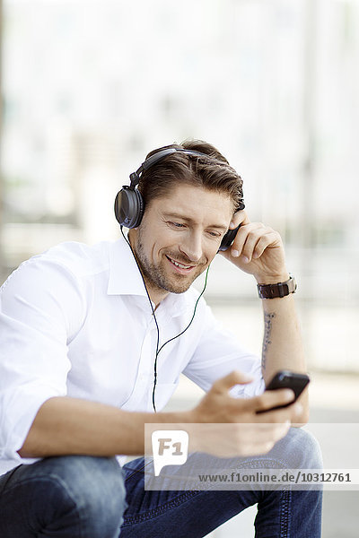Portrait of smiling man hearing music with MP3 Player and headphones