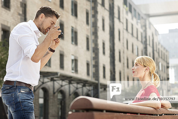 Man taking a picture of his girlfriend with a camera