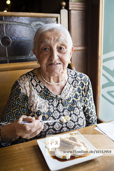 Senior woman eating caramel custard in a restaurant