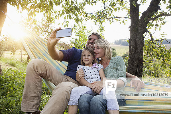 Glückliche Familie  die Selfie in der Hängematte nimmt