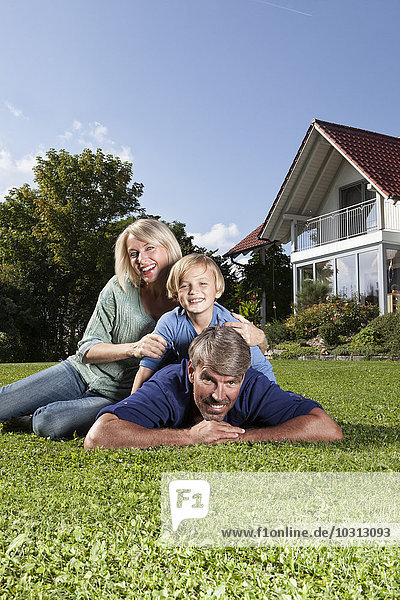 Happy family lying on lawn in garden