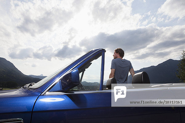 Germany  Bavaria  man next to convertible looking at view