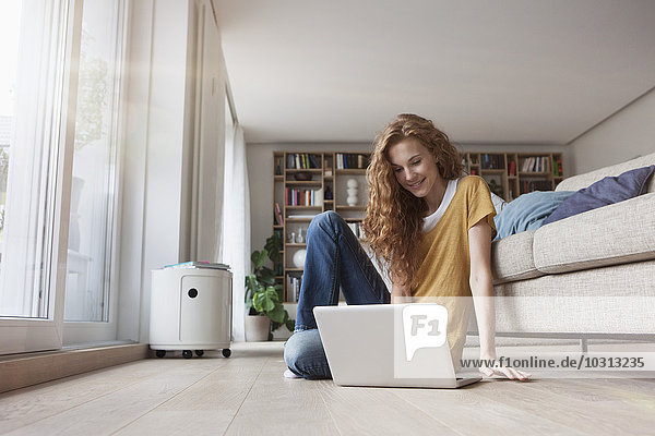 Woman at home sitting on floor using laptop