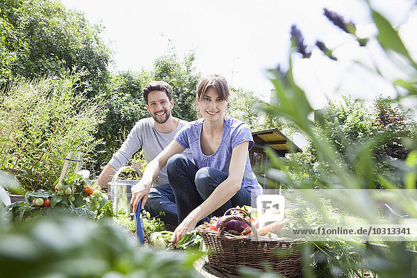Lächelndes Paar beim Gärtnern im Gemüsebeet