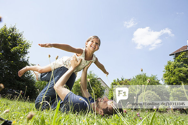 Father playing with daughter in garden
