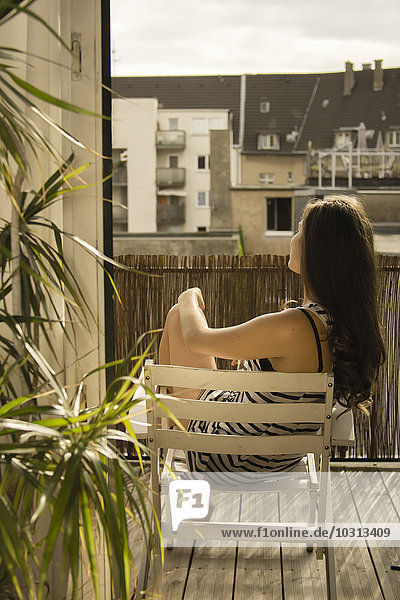 Deutschland,  Junge Frau beim Sonnenbaden auf dem Balkon