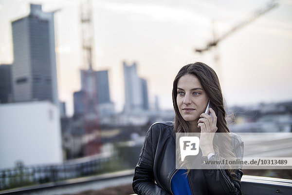 Deutschland  Frankfurt  Portrait einer jungen Frau beim Telefonieren mit dem Smartphone