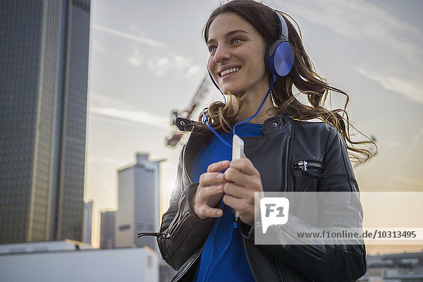 Deutschland  Frankfurt  lächelnde Frau beim Musikhören mit Kopfhörern beim Tanzen