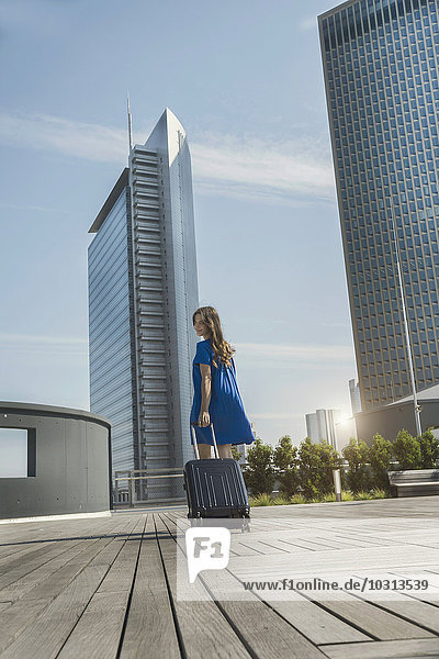 Deutschland  Frankfurt  Geschäftsfrau mit Smartphone und Rollgepäck auf der Dachterrasse