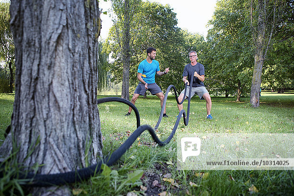 Man training with battle rope while his personal trainer watching him