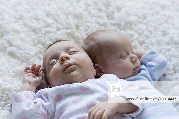 Portrait of sleeping newborn baby girl lying besides her twin brother