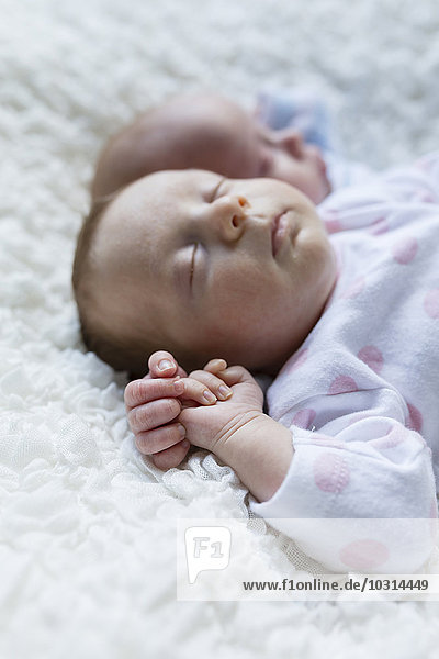 Porträt eines schlafenden neugeborenen Mädchens  das neben seinem Zwillingsbruder liegt.