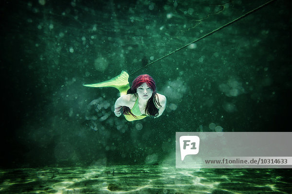 Young woman in the disguise of Arielle  the little mermaid  underwater