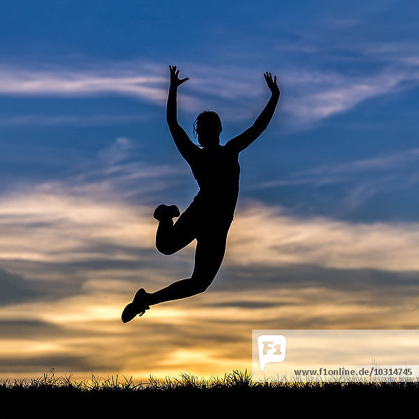 Germany  Silhouette of a woman jumping at sunset