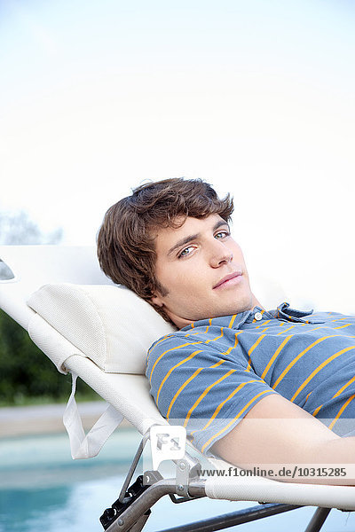 Young man relaxing on deckchair at the poolside