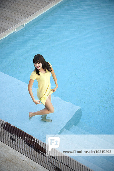 Happy young woman standing in swimming pool