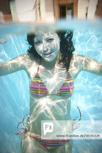Portrait einer jungen Frau unter Wasser im Schwimmbad
