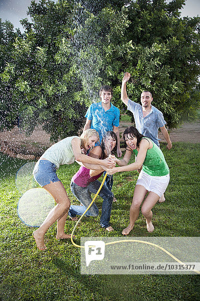 Five friends splashing with water in the garden