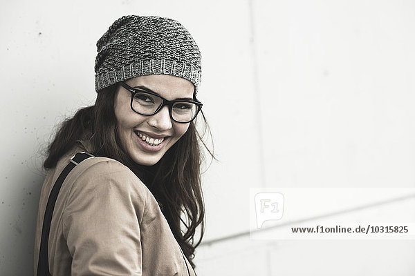 Porträt einer lächelnden jungen Frau mit Brille und Wollmütze