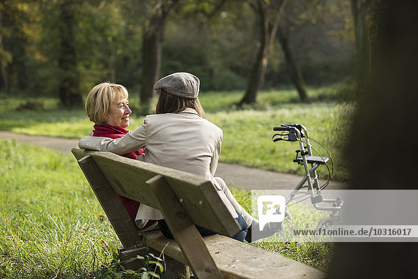 Senior woman and granddaughter sitting on a park bench