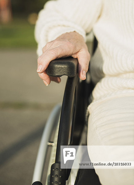 Hand of senior woman on armrest of wheelchair