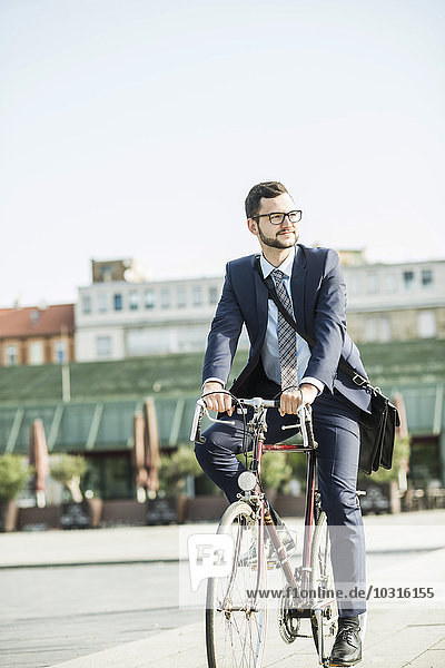 Young businessman riding bicycle