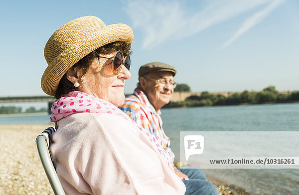 Deutschland  Ludwigshafen  Seniorenpaar auf Klappstühlen am Flussufer sitzend