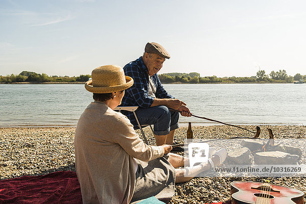 Germany  Ludwigshafen  senior couple barbecueing sausages on the beach