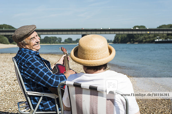 Deutschland  Ludwigshafen  Seniorenpaar mit Gitarre am Flussufer