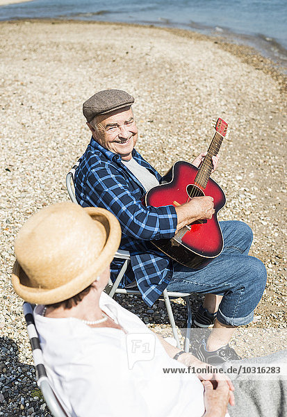 Deutschland  Ludwigshafen  Porträt eines lächelnden älteren Mannes mit Gitarre neben seiner Frau am Flussufer
