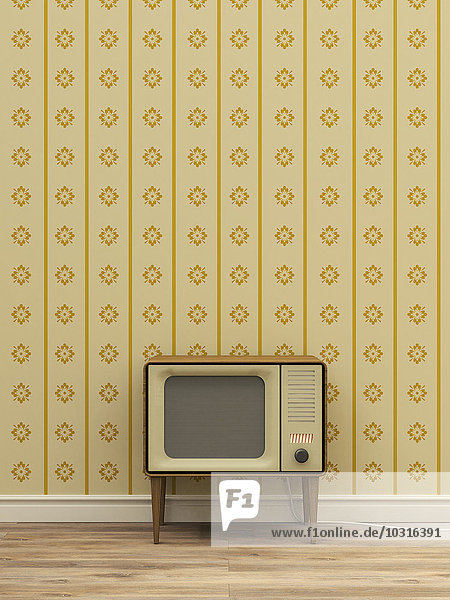 Old television in front of yellow patterned wallpaper