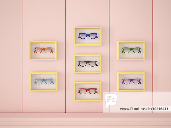 Bunte Gläser in gelben Rahmen an rosa Wand hängend