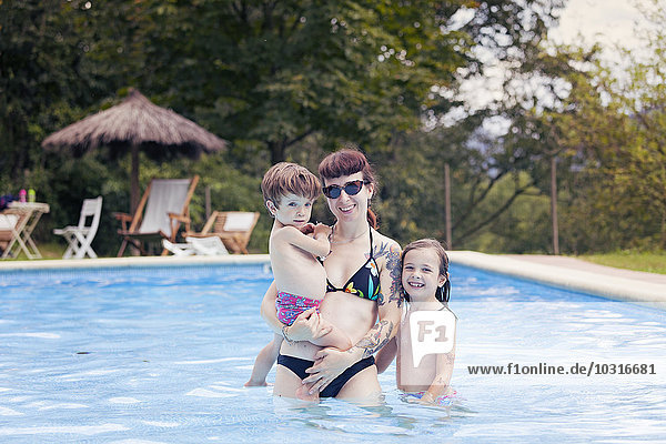 Tattooed woman with her children in swimming pool