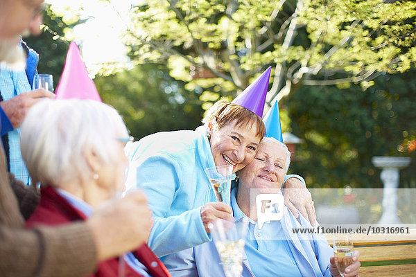 Seniorenfreunde beim Umarmen auf einer Geburtstagsgartenparty