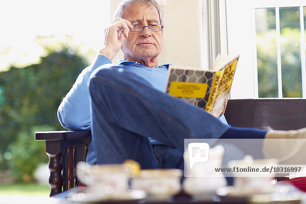 Älterer Mann liest Buch zu Hause