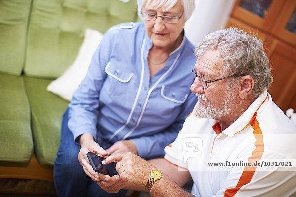 Seniorenpaar mit Smartphone zu Hause