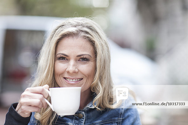 Porträt einer lächelnden Frau beim Kaffeetrinken