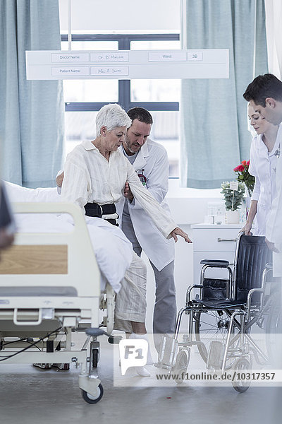 Arzt und Personal helfen Patienten mit Rollstuhl im Krankenhaus