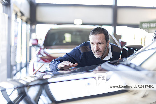 Mann untersucht neues Auto im Autohaus