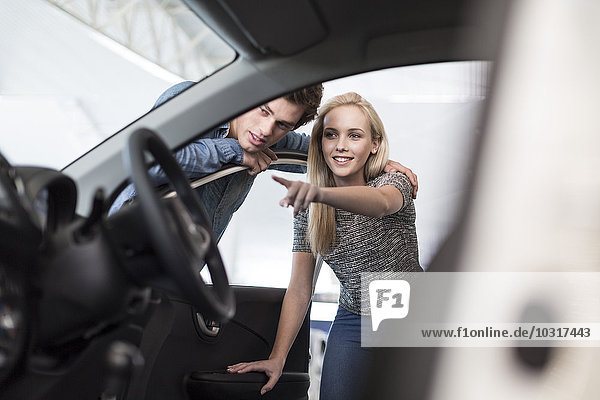 Junges Ehepaar untersucht neues Auto im Autohaus