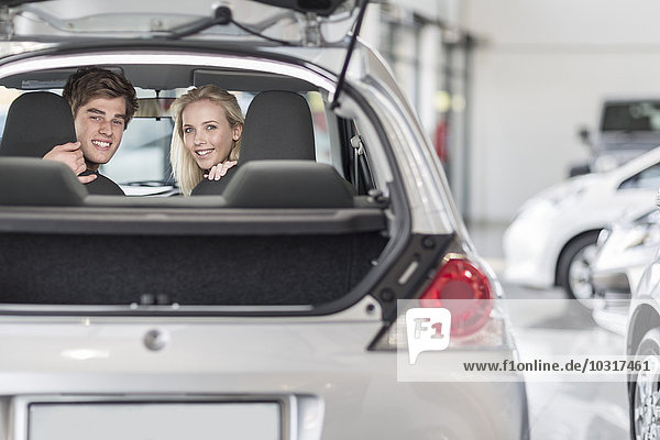 Young couple sitting in new car at car dealership