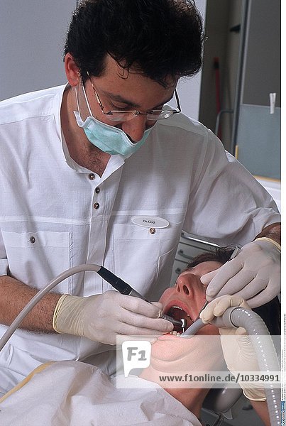 Zahnarztpraxis  Zahnarzt bearbeitet den kariösen Zahn eines Patienten mit einem Bohrer