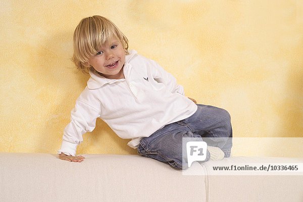 Kind sitzt auf einem Sofa und lacht