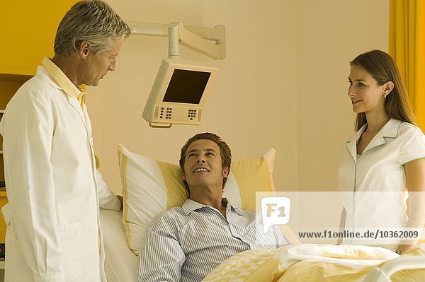 Arzt spricht mit Mann im Krankenhausbett