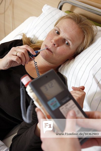 Die Krankenschwester prüft die Körpertemperatur eines Patienten in einem Krankenhaus