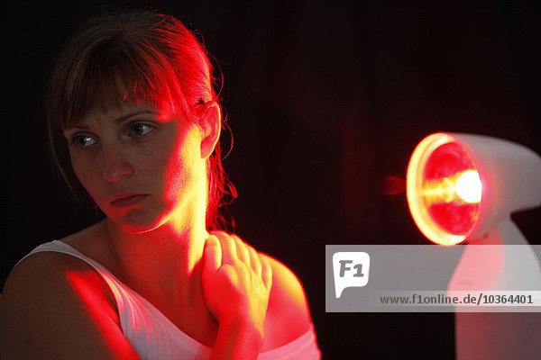 Junge erwachsene Frau lässt sich von einer ultravioletten heißen Lite-Lampe beleuchten  gegen Erkältungen  Versteifungen  Schmerzen