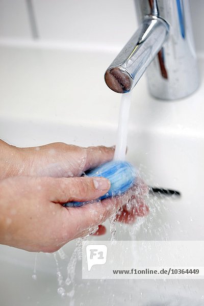 Die Hände werden in einem Handwaschbecken mit Wasser und Seife gewaschen.