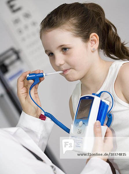 Kinderarzt  der ein Mädchen untersucht und seine Temperatur misst.