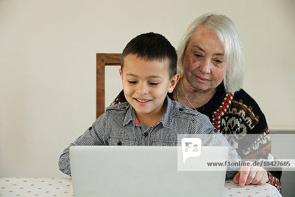 6-jähriger Junge sieht sich mit seiner Großmutter einen Laptop an